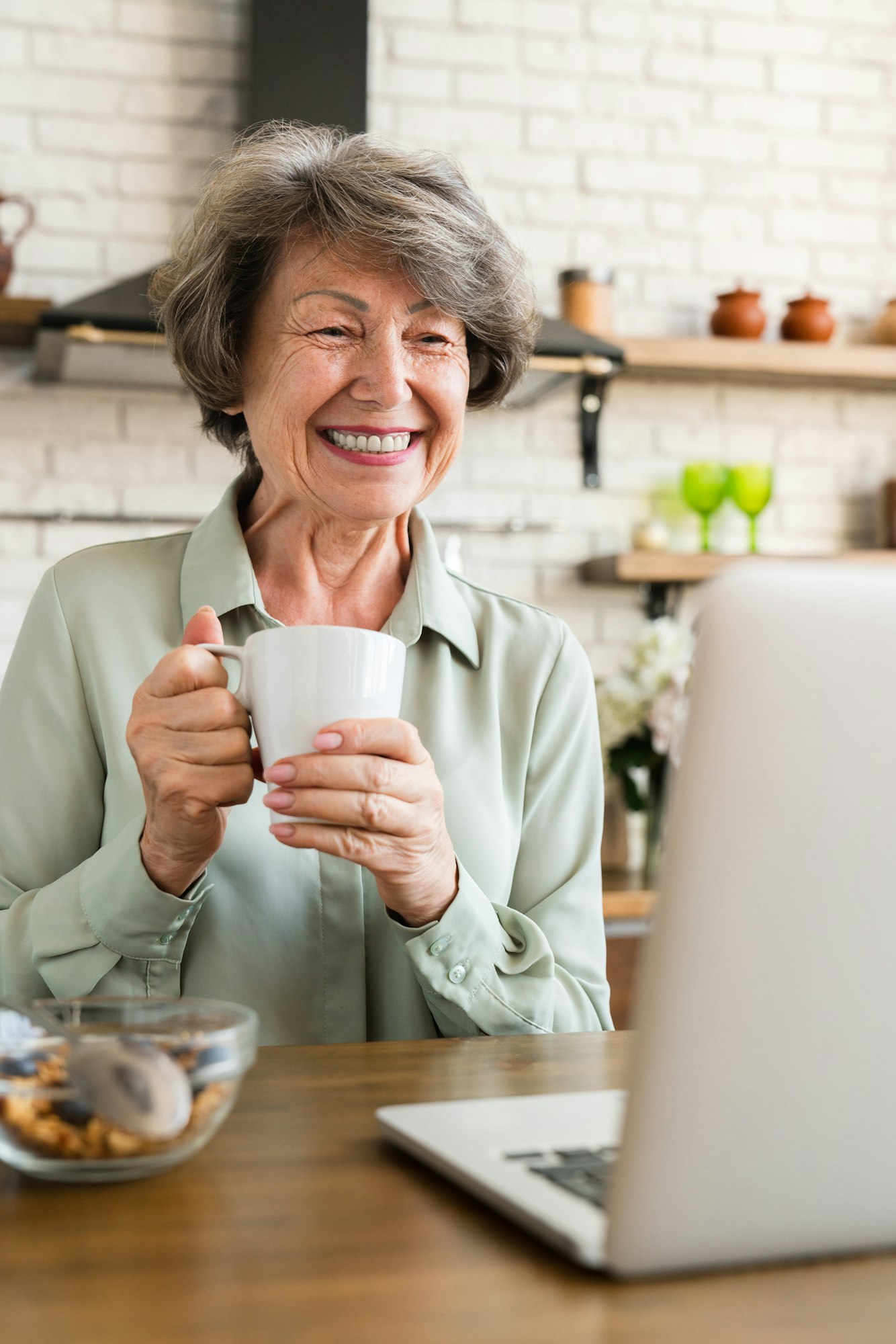 Cheerful happy grandmother having breakfast at home kitchen.