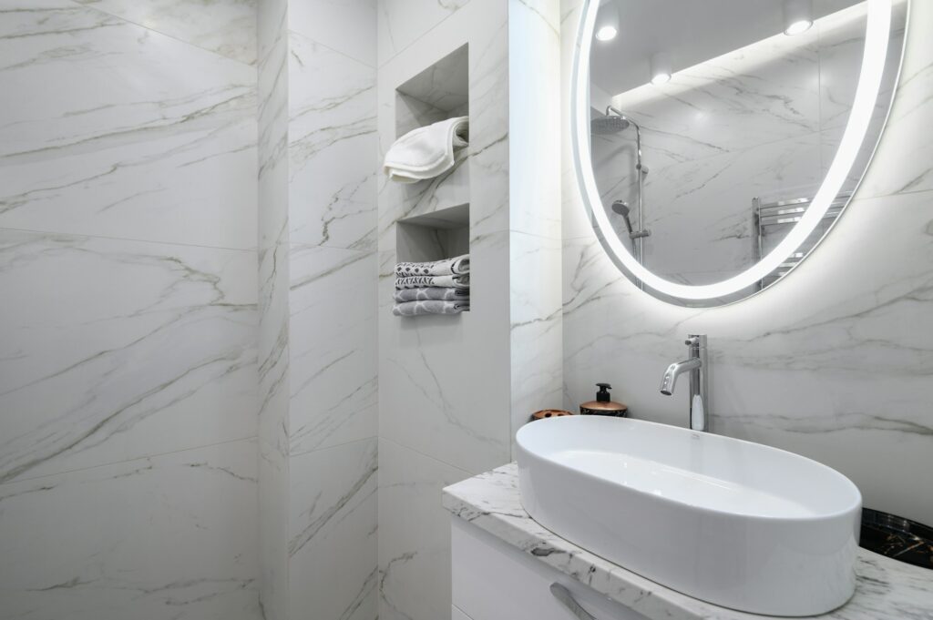 White bathroom interior with marble tiles on the walls